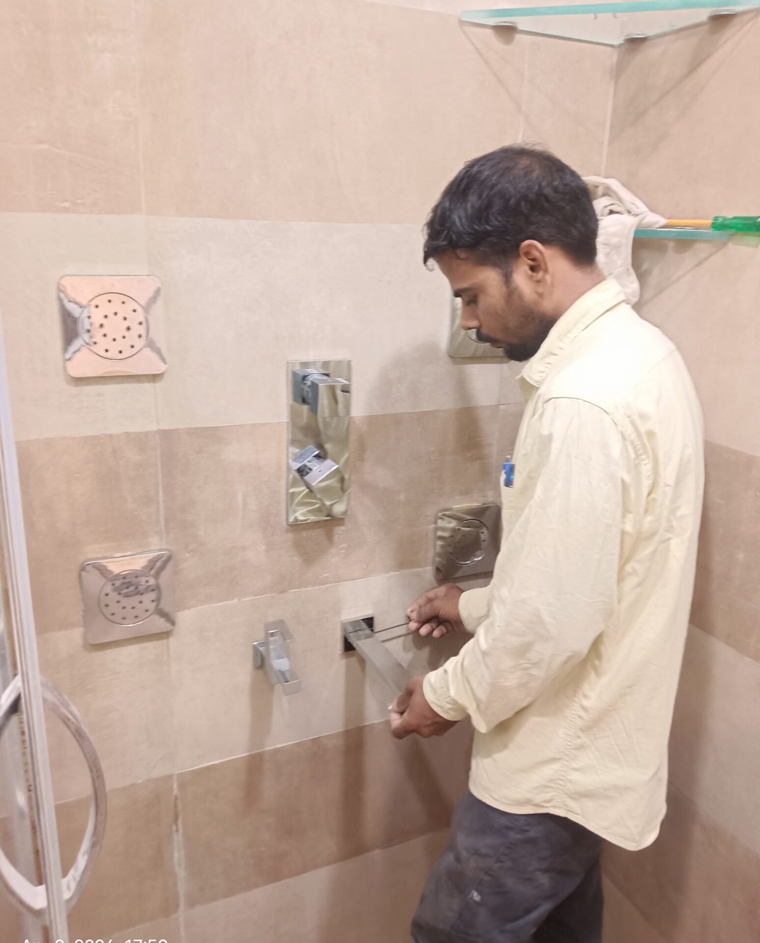 Professional body shower installation in a modern tiled bathroom, featuring multiple wall-mounted body jets, a handheld shower, and a sleek control panel. A technician is adjusting the shower system, highlighting expert plumbing, luxury bathroom upgrades, and contemporary shower design.